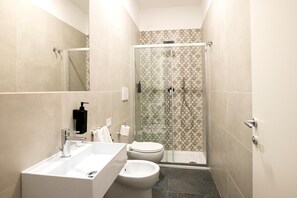 Ein modernes Badezimmer mit Duschkabine, Waschbecken, Toilette und Bidet.