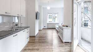 Une cuisine moderne avec des armoires blanches, un plan de travail noir et un plancher en bois.