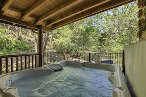 A hot tub with a wooden roof and a metal railing, surrounded by lush greenery. - Timberstone 4 Bedroom Home (Sevierville)