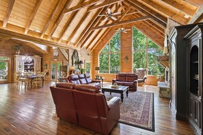 A spacious loft with high ceilings, wooden beams, a fireplace, leather sofas, and large windows. - Timberstone 4 Bedroom Home (Sevierville)
