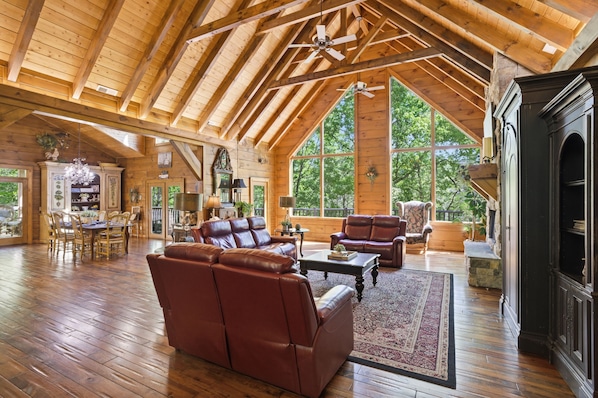 A spacious loft with high ceilings, wooden beams, a fireplace, leather sofas, and large windows. - Timberstone 4 Bedroom Home (Sevierville)