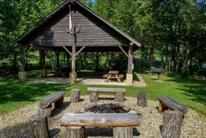 A rustic wooden pavilion with a fire pit in the center, surrounded by benches. - Timberstone 4 Bedroom Home (Sevierville)