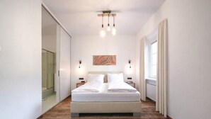 Ein modernes Schlafzimmer mit einem großen Bett, Holzboden und einer Glasdusche.