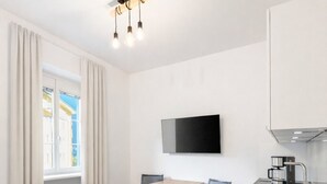 Eine moderne Küche mit Holztisch, zwei Stühlen, einer eingebauten Spüle und einem flachbildfernseher an der Wand.