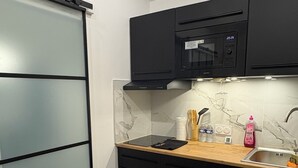 A modern kitchen with black cabinets, a microwave, and a wooden countertop. - Exclusive getaway with pool and jacuzzi (Clermont)
