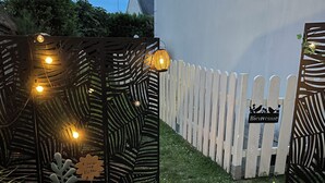 A garden area with a decorative metal fence, a white picket fence, and a sign that reads 'Bienvenue.' - Exclusive getaway with pool and jacuzzi (Clermont)