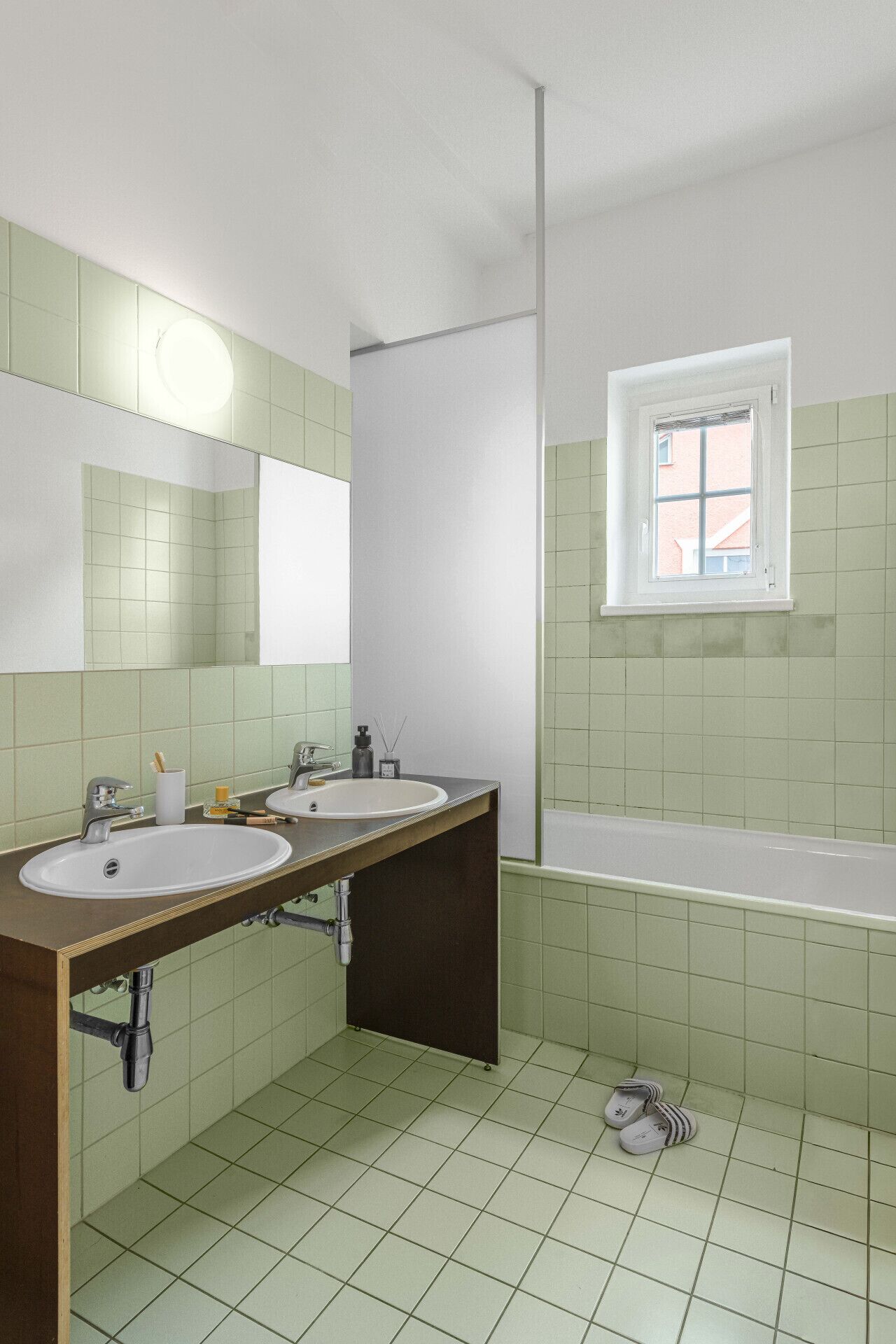 Une salle de bain avec deux lavabos, un miroir, une fenêtre et une baignoire.