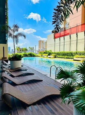 A swimming pool with lounge chairs and potted plants. - MJM Cityscape At Red Residences Makati (Makati)