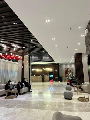 A modern lobby with a reception desk, seating area, and a Christmas tree. - MJM Cityscape At Red Residences Makati (Makati)