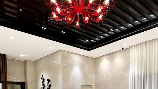 A modern living room with a large sectional sofa, a glass coffee table, and a red chandelier. - MJM Cityscape At Red Residences Makati (Makati)