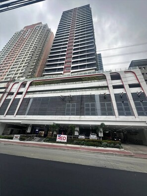 A modern building with multiple floors, large windows, and a prominent entrance area. - MJM Cityscape At Red Residences Makati (Makati)