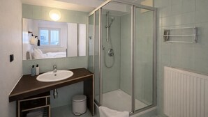 Ein modernes Badezimmer mit einer Duschkabine, einem Waschbecken mit Spiegel und einem Handtuchhalter.