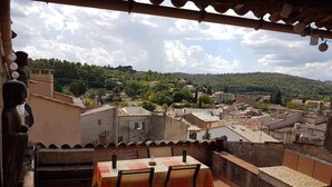 Una terraza con mesa y sillas, con vistas a un pueblo con edificios tradicionales y una colina al fondo.