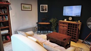 A living room with a sofa, a wooden cabinet, a television, and a bookshelf. - Groombridge 1 Bed Self Catered Flat, can Sleep 4 (Royal Tunbridge Wells)
