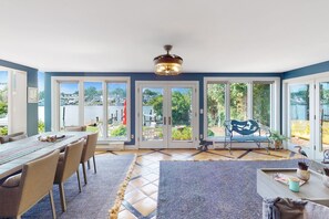 Comedor con una mesa grande, sillas y vistas al exterior a través de puertas de vidrio.