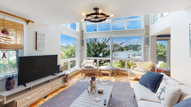 Amplia sala de estar con televisor grande, asientos cómodos y ventanas grandes que ofrecen vistas al exterior.