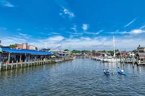 Puerto deportivo con barcos, un muelle y un edificio con toldo azul.