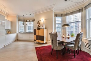 A modern kitchen with white cabinets, a red rug, and a dining area with a table and chairs. - 3-bed Knightsbridge Harrods View Best Location (London)