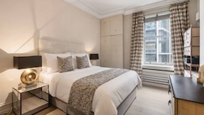 Une chambre moderne avec un grand lit, des tables de chevet, une fenêtre avec des rideaux et des rangements intégrés.