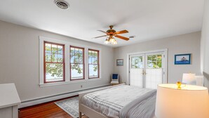 A bedroom with a bed, a ceiling fan, a window, and a lamp. - Waterfront home with scenic porches, yard, grill, jetted tub, central AC, & W/D (Annapolis)