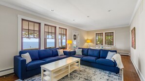 A living room with a blue sofa, a white coffee table, and a patterned rug. - Waterfront home with scenic porches, yard, grill, jetted tub, central AC, & W/D (Annapolis)