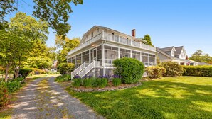 A large house with a covered porch, a gravel driveway, and well-maintained lawns. - Waterfront home with scenic porches, yard, grill, jetted tub, central AC, & W/D (Annapolis)