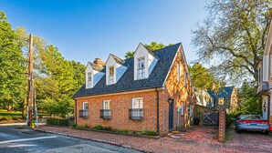 A traditional brick house with a gabled roof and dormer windows, a brick driveway, and a gated entrance. - Charming brick home with patio, WiFi, AC, & W/D - walk to everything (Annapolis)