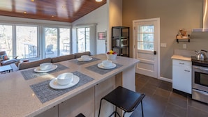 A modern kitchen with a central island, built-in appliances, and large windows.