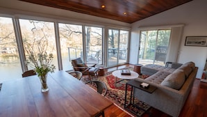 A spacious living area with a wooden dining table, a gray sofa, and a view of a deck and outdoor furniture.
