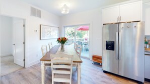 Una cocina con una mesa de comedor de madera, armarios blancos y un refrigerador de acero inoxidable.