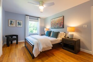 A bedroom with a bed, bedside tables, a chair, a ceiling fan, and artwork on the walls. - Spacious home with an outdoor pool, screened porch, washer/dryer & central AC (Annapolis)