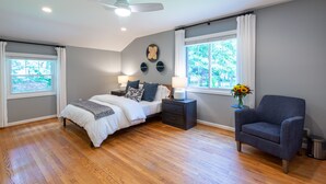 Ein Schlafzimmer mit Bett, Nachttischen, einem Sessel und einem Deckenventilator.