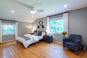 Ein Schlafzimmer mit Bett, Nachttischen, einem Sessel und einem Deckenventilator.