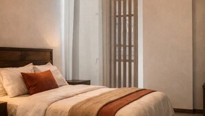 A bedroom with a wooden bed, a bedside table, a hanging light fixture, and a window with blinds. - Luxury STUDIO, Executive 3 minutes from the park (Quito)
