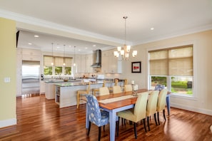 A spacious kitchen with a central island, wooden flooring, and a dining area with six chairs. - Spacious beachfront home with decks, gas grill, wet bar, gas fireplace, and W/D (Annapolis)