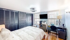 Een slaapkamer met een bed, een bureau, een stoel en een kledingkast.