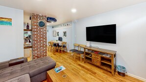 Een woonkamer met een bank, televisie, houten tafel en een metselwerk scheidingswand.