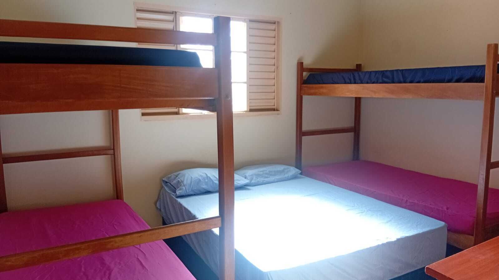 A bunk bed room with a window and a desk.