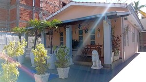 A small building with a covered porch, potted plants, a statue, and a wooden bench. - House in Rifaina, with swimming pool, close to the beach. (Rifaina)