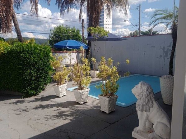 A pool area with potted plants and a white statue.