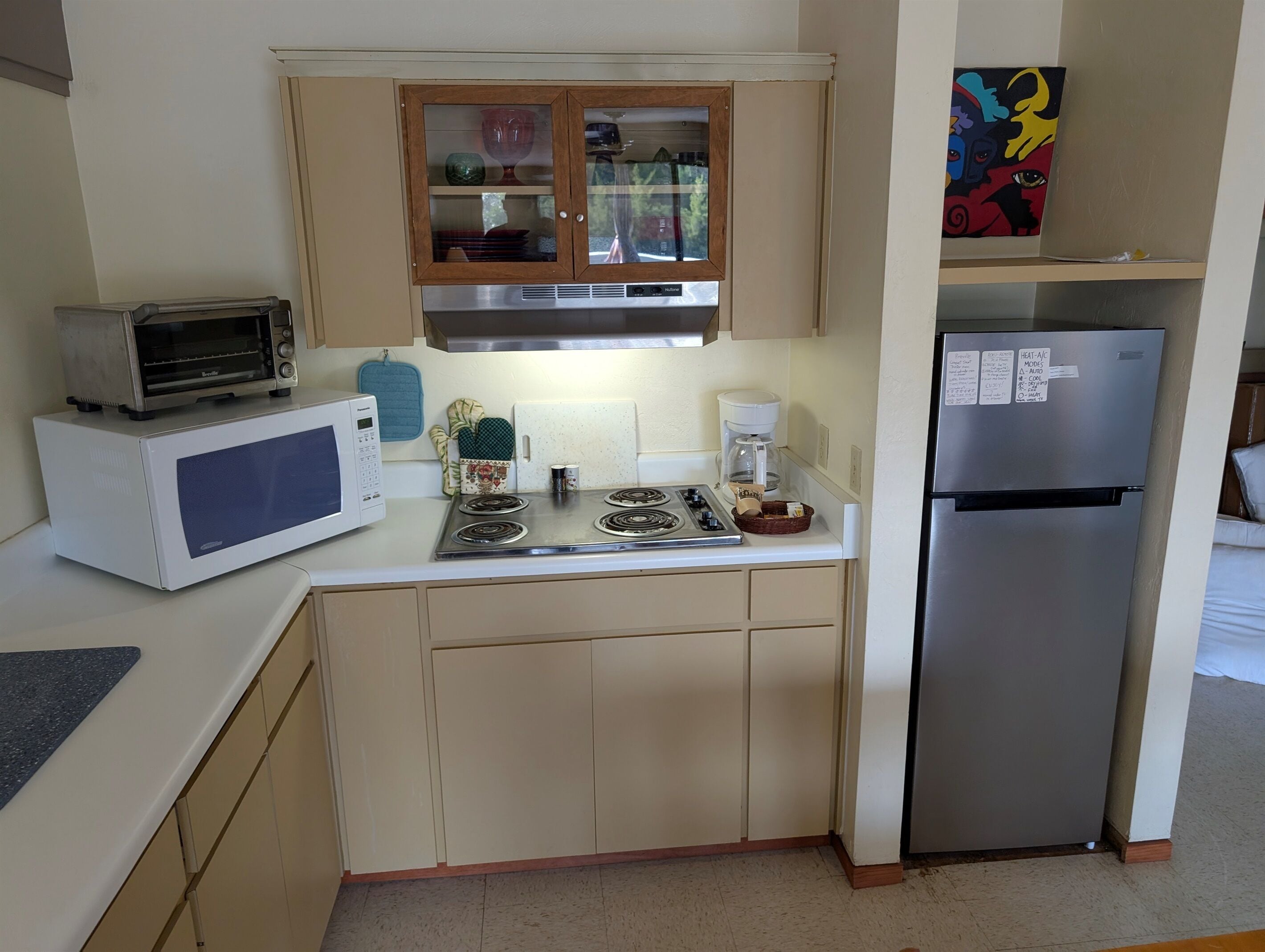 A compact kitchen with a microwave, toaster, stove, and refrigerator.