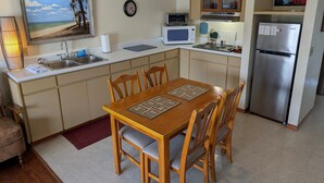 Une cuisine compacte avec un coin repas, équipée d’un four à micro-ondes, d’un grille-pain et d’un réfrigérateur.