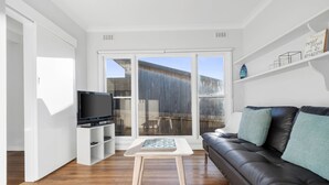 A modern living room with a leather sofa, a flat-screen TV, and a coffee table. - Days by the Bay (Apollo Bay)