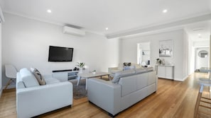 A modern living room with a grey sectional sofa, a flat-screen TV mounted on the wall, and a small coffee table. - Days by the Bay for relaxed and easy living (Apollo Bay)
