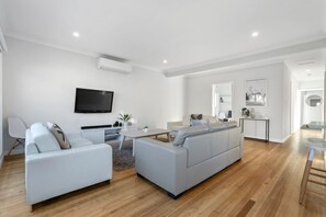 A modern living room with a flat-screen TV, two sofas, a coffee table, and a small side table. - Days by the Bay (Apollo Bay)
