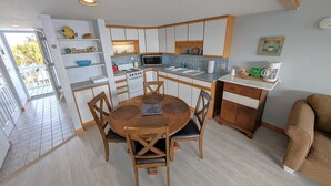 A compact kitchen with a dining area, a microwave, a stove, and a coffee maker. - Park Place -Parkside Dream -Downtown w/ Gulf View! (Cedar Key)