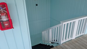 A blue wooden staircase with a white railing leading to an upper level. - Park Place -Parkside Dream -Downtown w/ Gulf View! (Cedar Key)