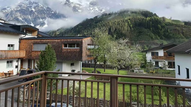 Ein Wohngebiet mit Häusern, einem Balkon und Berglage im Hintergrund.