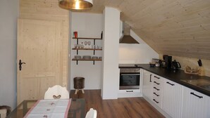 Eine kleine Küche mit Holzausstattung, einem eingebauten Ofen und einer Pendelleuchte.