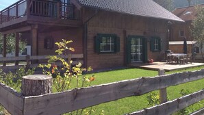 Ein Holzhaus mit Balkon, grünen Fensterläden und einer Holzterrasse.